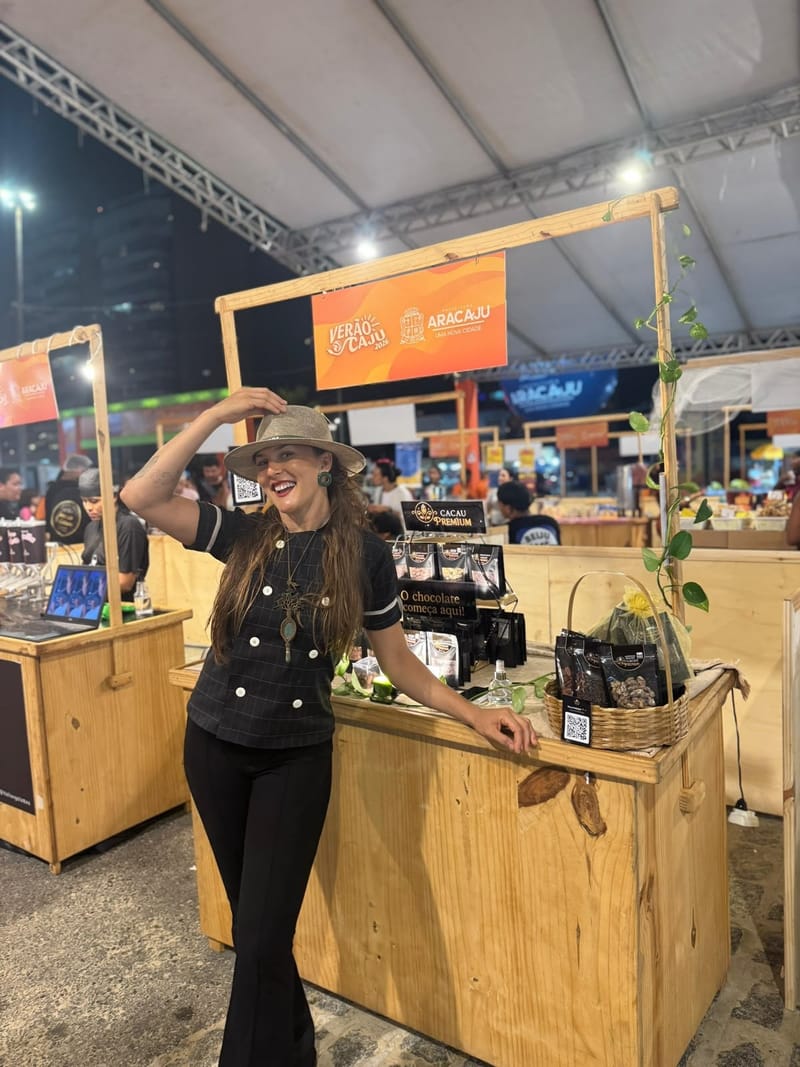 Wegilla Caroline na barraca da Cacau Premium montada no Verão Aracaju, com os produtos expostos