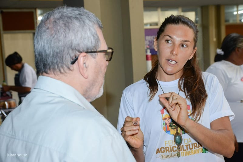 Wegilla explicando os produtos de cacau a um visitante da feira